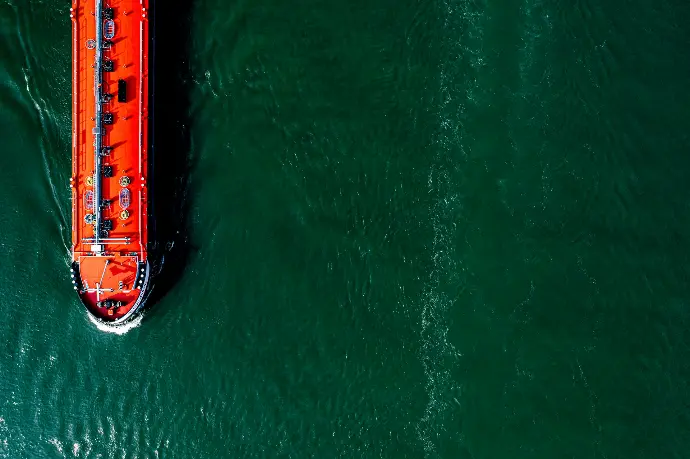 an orange boat floating on top of a body of water